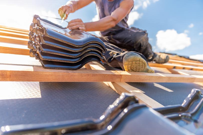 A roofer applying a roof coating to a commercial building